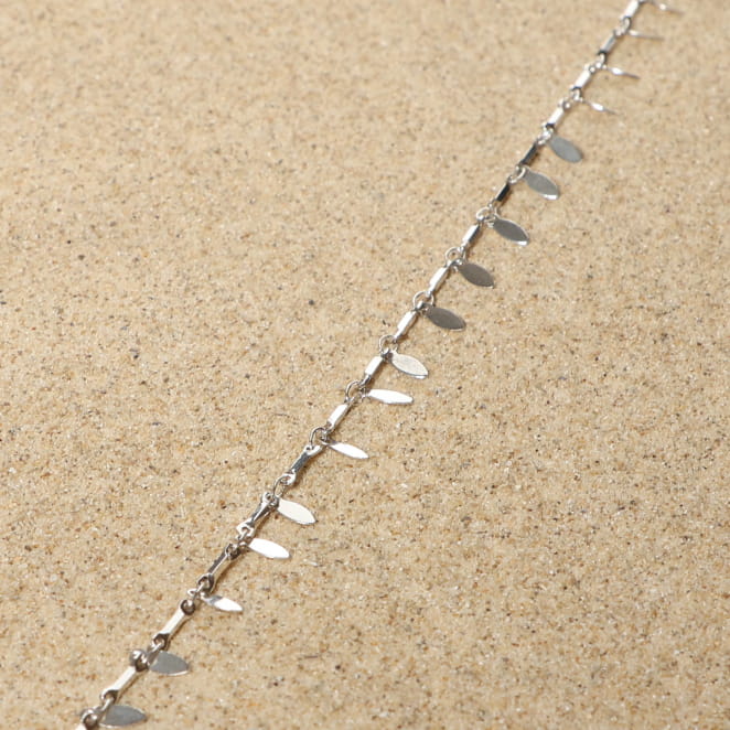 bracelet de cheville Feuillage argenté avec maillons feuillus posé sur tissu clair