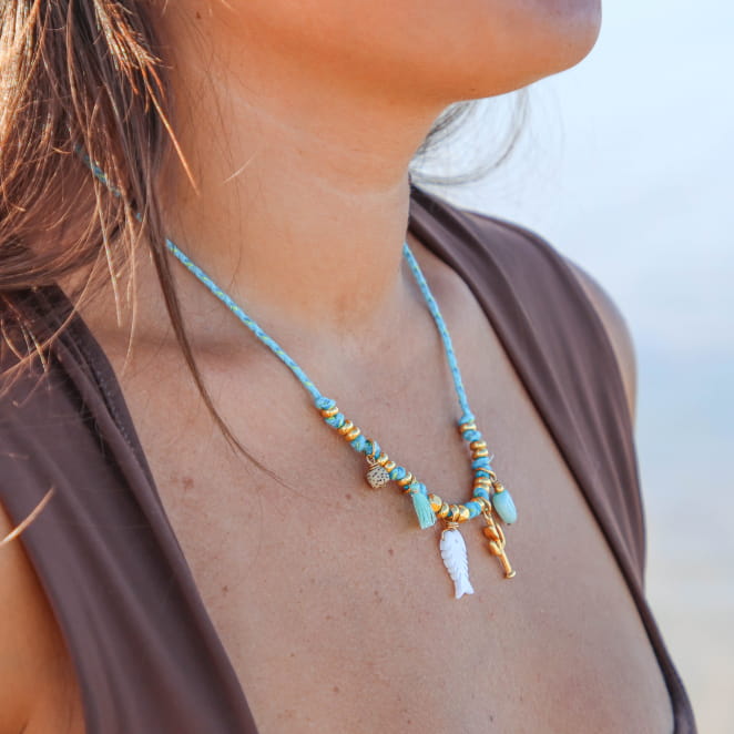 collier Bachata doré et turquoise porté avec chemise ouverte, détails raffinés