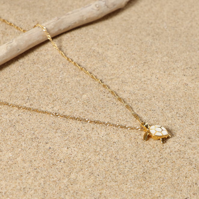 Collier doré en chaine fine avec un pendentif tortue éaillé blanc cassé.