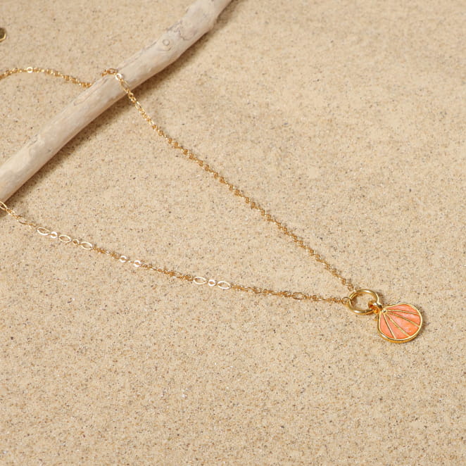 collier Caliope doré orné d’un pendentif perle corail sur sable clair