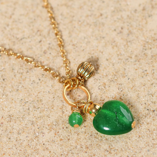 Collier Dimanche doré, deux pampilles vert émeraude brillantes, posées sur sable – bijou élégant fabriqué en France