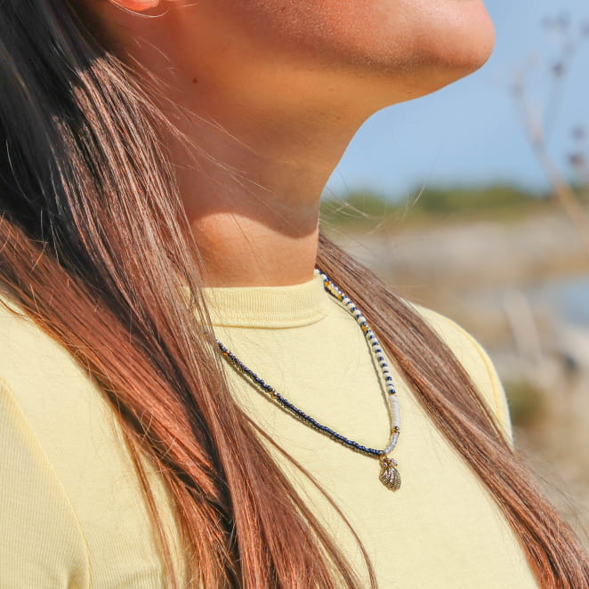 collier Domino doré à perles noires porté sur buste