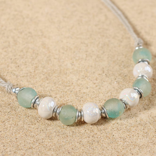 Gros plan sur le collier Euskara argenté, perles blanches et fermoir visible – création française