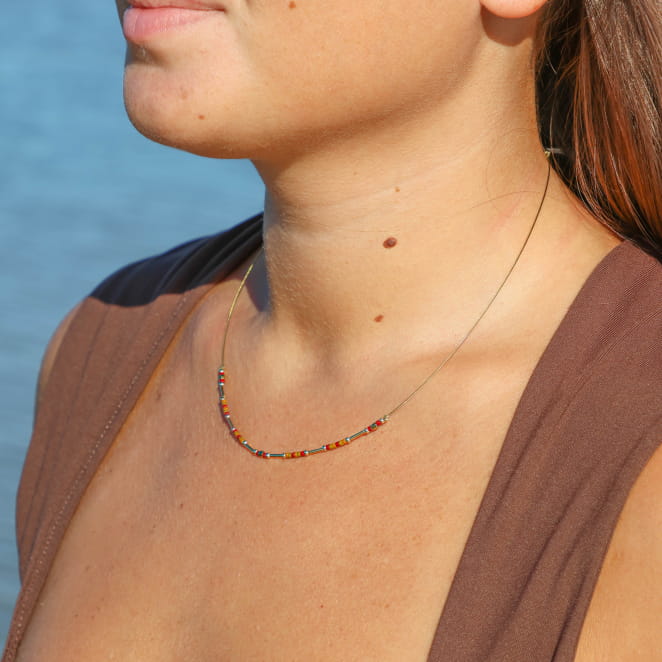 collier Huari doré et rouge porté sur buste en haut marron