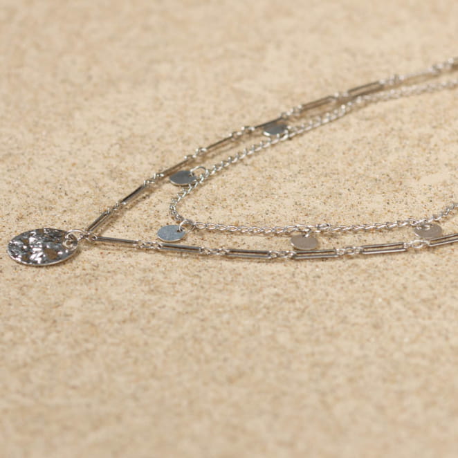 Collier Loustic en métal argenté, maille légère et petit pendentif texturé.