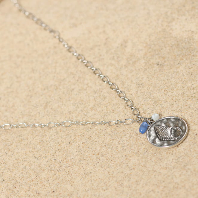 Collier Pêche argenté avec pendentif bleu ciel scintillant, présenté en extérieur – création artisanale