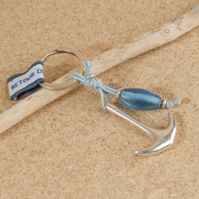 Zoom sur porte-clés Bourcefranc bleu ciel et argent, posé sur le sable – fait main en France