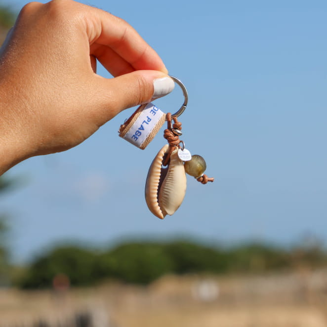 porte-clés Kory argenté avec coquillage beige tenu en main