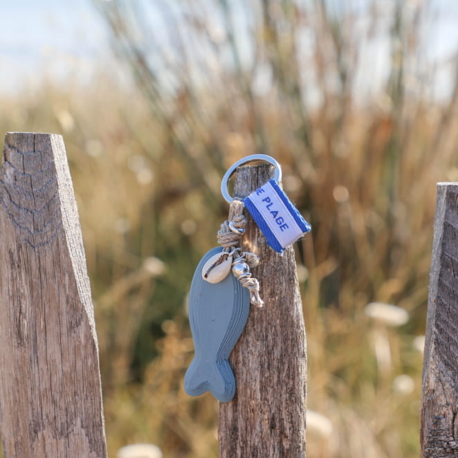 porte-clés Pilou argenté avec détails bleu tenu en main