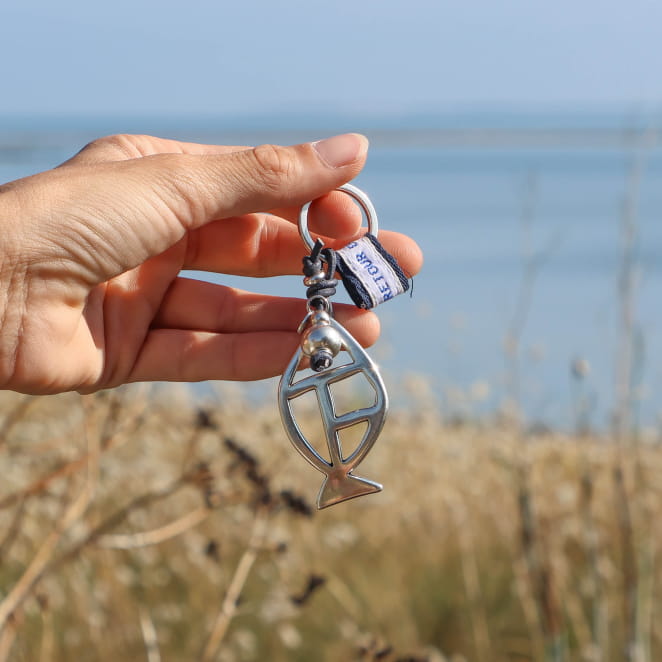 porte-clés Merlan argenté et bleu marine tenu en main