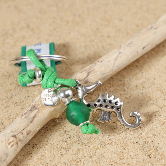 Gros plan sur l'hippocampe en métal plaqué argent 999 et la perle en métal plaqué argent 999 du porte-clés Otago, avec perle en verre recyclé vert et médaille Retour de Plage.